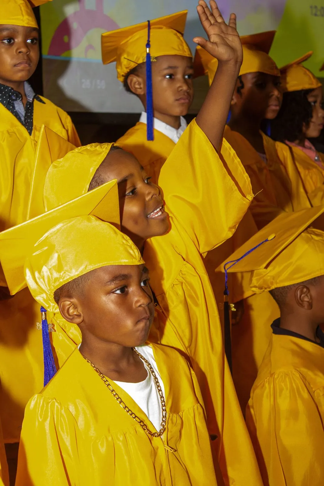 Kindergarten graduates in yellow caps and gowns