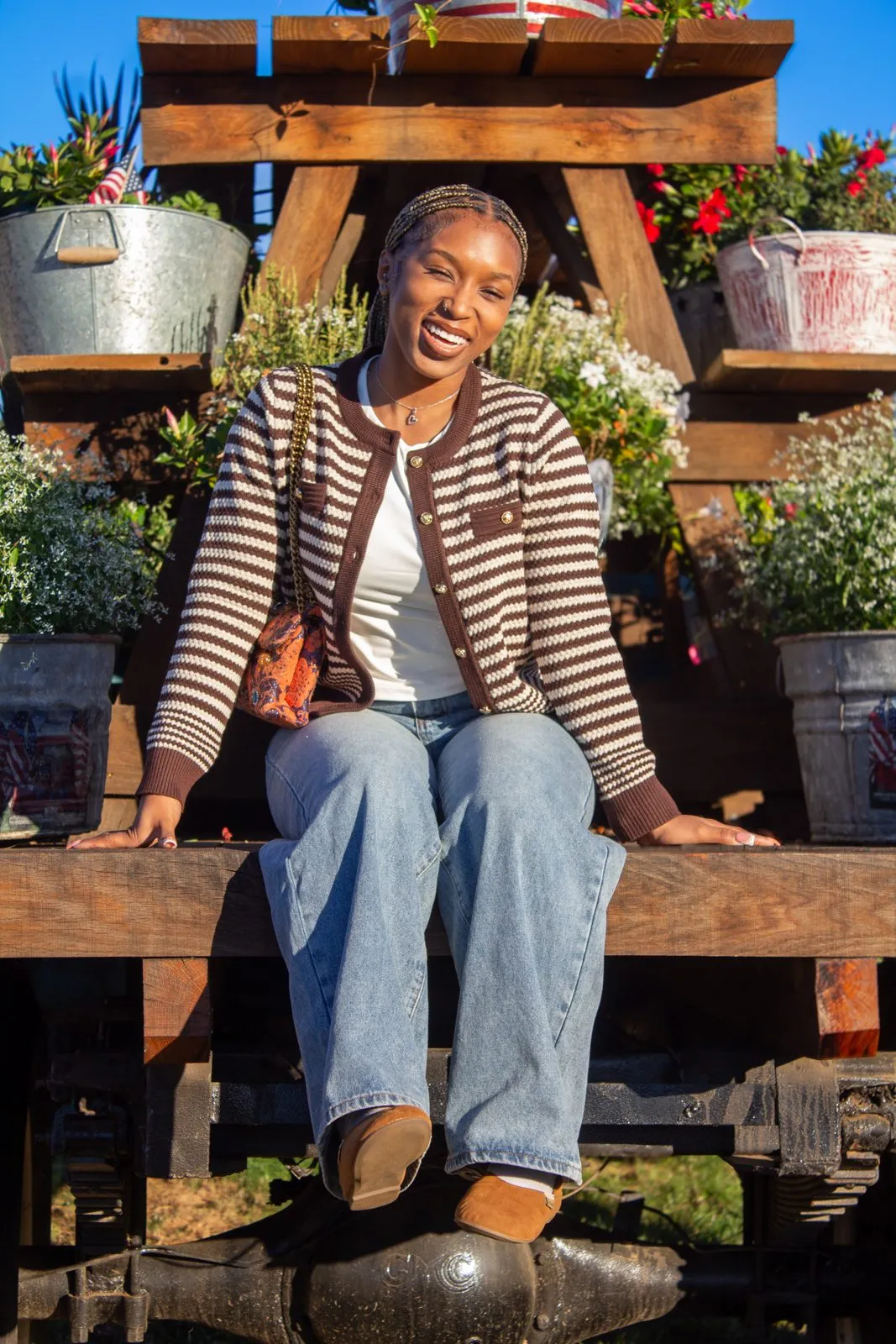 Woman seated on a wooden flower stand in warm sunlight